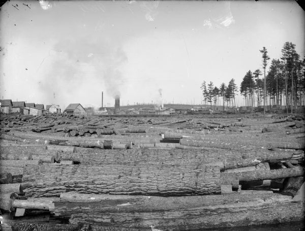 Lumberyard full of logs and a sawmill in the distance, probably McKenna in eastern Jackson County.