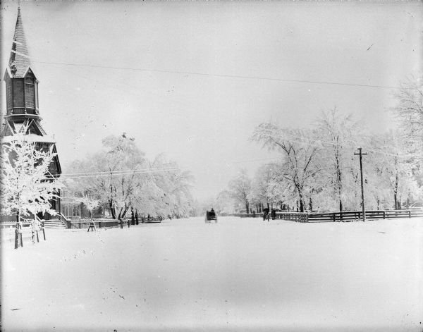 Winter scene with a man driving a wagon pulled by a single horse down a snow-covered road past a group of people and a church, possibly the Methodist Episcopal Church.