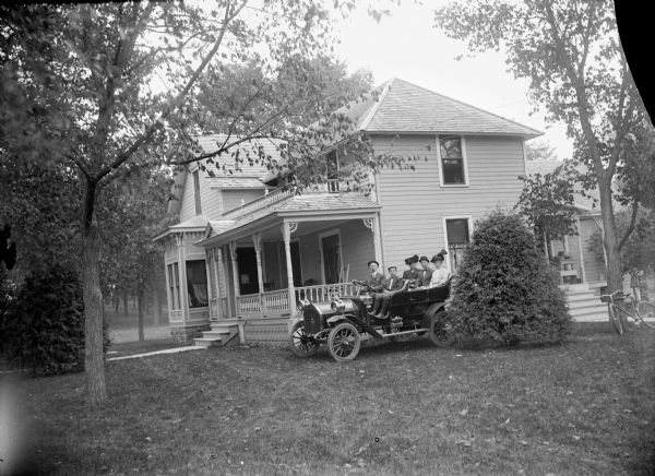 Two men, two women, and a boy are posing sitting in an automobile parked in the yard next to a frame house. Probably Eugene J. Greenlee and son Eugene in the front, and Mrs. Greenlee, Byron Greenlee, and Irma Greenlee Reichenbach in the back seat. The automobile is probably "The Silent Northern," which had two opposing cylinders and rode relatively quiet. Greenlee supposedly charged 25 cents for a ride to the fairgrounds.	