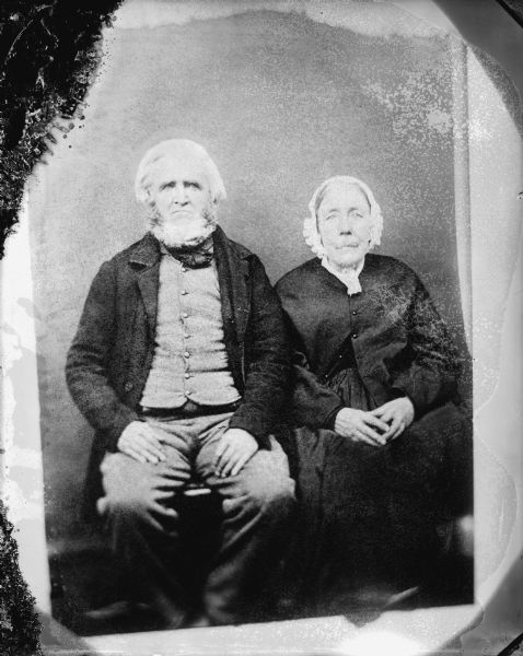 Copy photograph of a studio portrait of an elderly man and woman posed sitting.