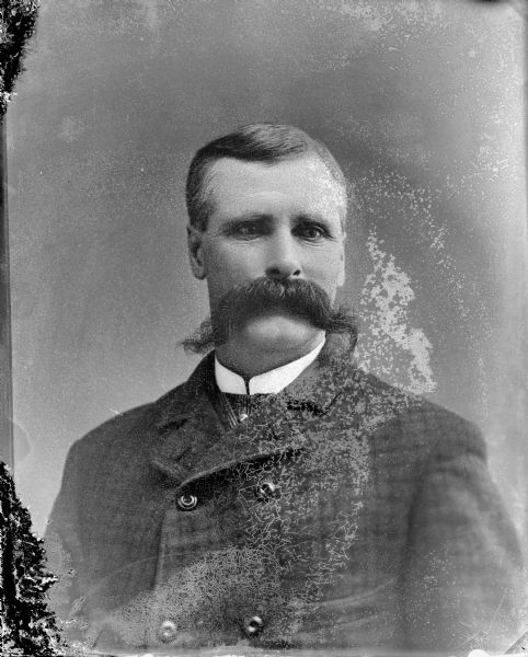 Quarter-length studio portrait of a man with a long moustache, possibly Brockwau.