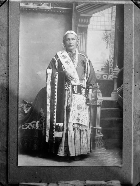 Copy photograph of a studio portrait of an elderly Native American woman posed standing and wearing native dress, possibly the second Mrs. Luke Snowball.