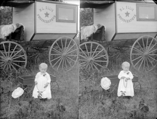 Glass negative with two images. Left, a small child by a child's wagon and the photography wagon of N.L. Ellis. Right, same components as the left image.
