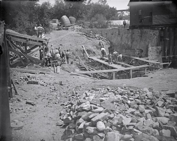 Men working on the foundation of a building, possibly laying a foundation for the post-flood business district dam.