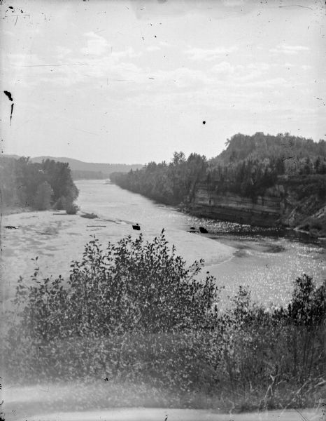 Elevated view of a river, with exposed rock bluffs along the shoreline on the right.	