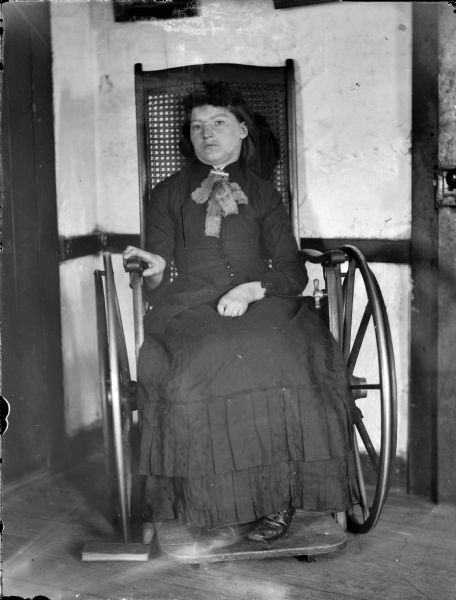 Portrait of a woman sitting in a wheelchair indoors.