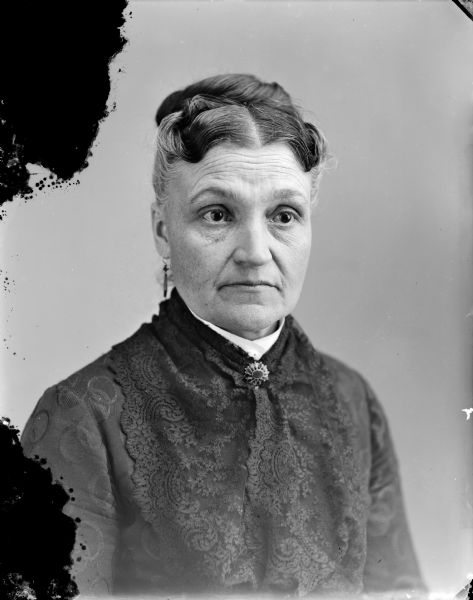 Waist-up studio portrait of an elderly woman posing sitting.