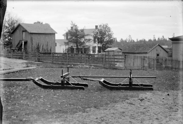 Exterior view of the runners of a Spaulding sleigh behind the wagon shop.