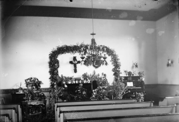 Interior view of a church from the rear, probably decorated for a funeral, with flowers arranged around the altar.