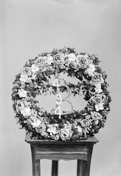 Studio portrait of a funeral wreath displayed on a table, with the numbers 494.