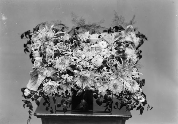 Studio photograph of a floral arrangement displayed on a table. Probably for a funeral.