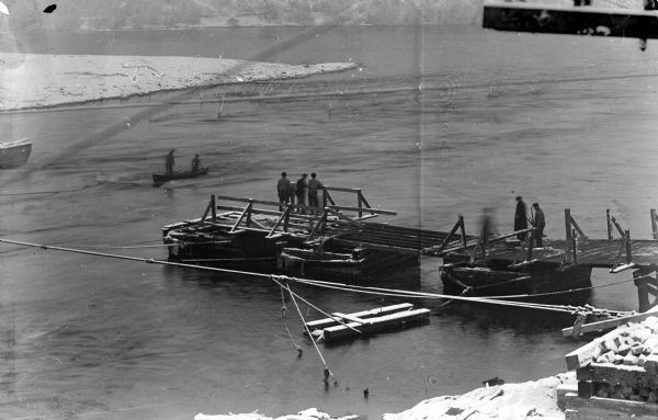 Elevated view of the construction of a pontoon bridge at the Fillmore Street in Black River Falls built by the railroad. It had broken apart and was later repaired.