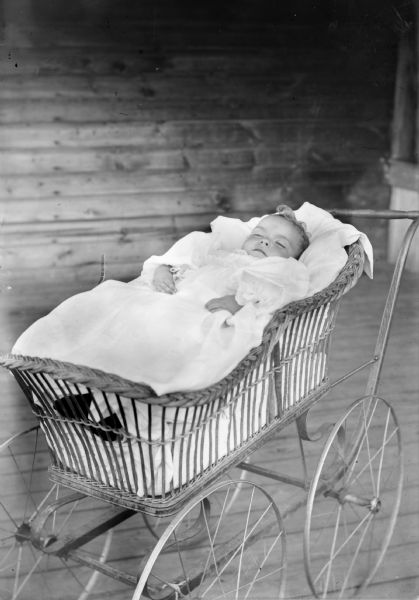 Interior view of an infant post mortem, lying in a baby buggy.