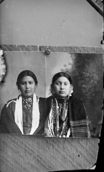 Copy of an existing photograph of a waist-up studio portrait of Mary (Whitedog) White Eagle and Fanny Youngswan. Both women are wearing several necklaces and fringed shawls.