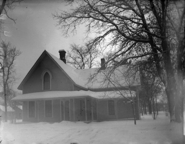 View across snowy yard towards a wooden house. Identified as the residence of Jedney C. Matthews before Adolph Homstad at 618 Main Street, southeast corner of Main and Seventh Streets.