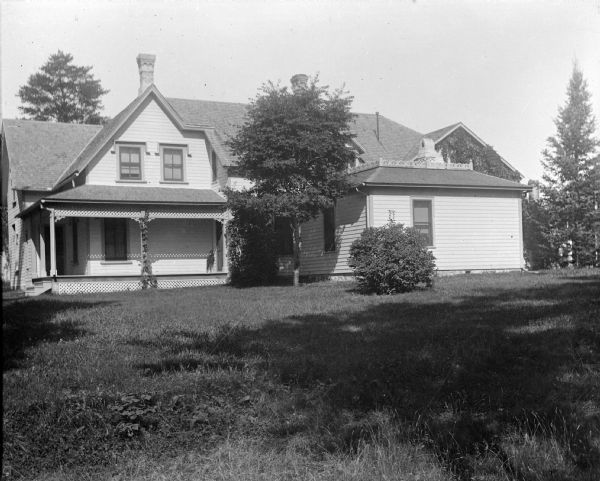 View across lawn towards a wooden house with a large yard. The house is identified as the residence of Rollin Jones at 703 Harrison Street.