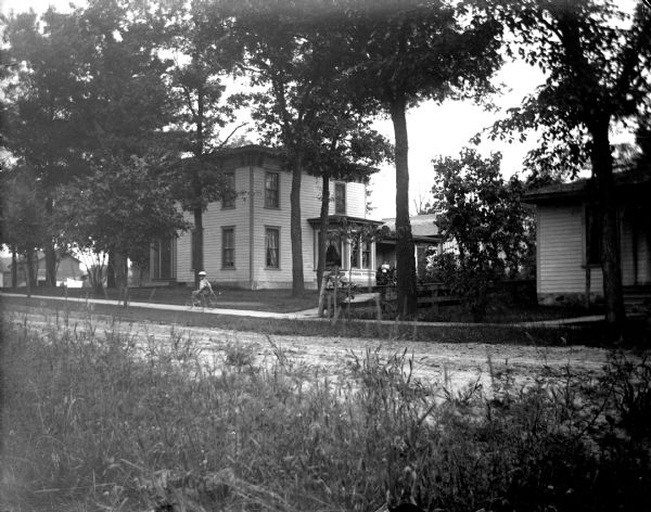 Exterior portrait of an individual in a wheel chair on a wooden walkway in front of a two-story house. House identified as the residence of Calvin Johnson on the northeast corner of Eighth and Taylor Streets.