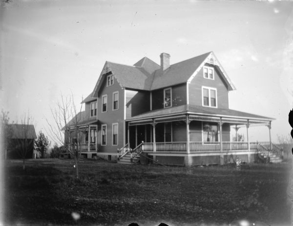 Exterior portrait of a two-story wooden house with a large yard.