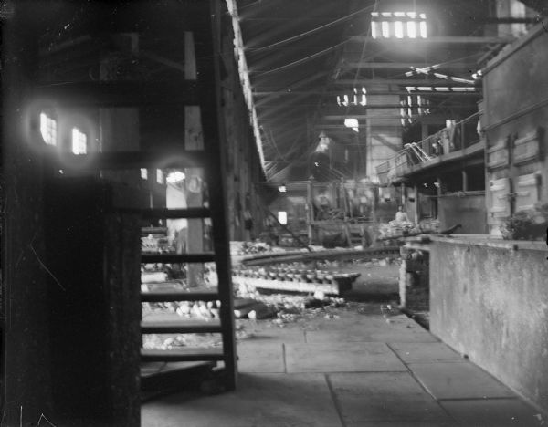Indoor view of a large industrial building, with a man posing standing in the distance. Identified as the interior of the York Iron Works.