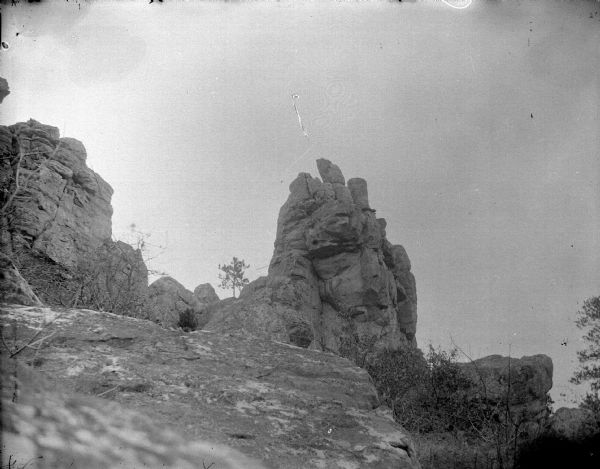 View looking up towards a rock formation on a hill. Location identified as Castle Mound.