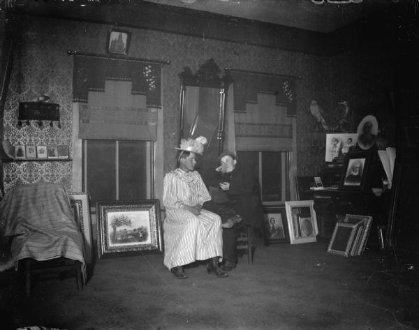 Interior view of a two men posing sitting in front of windows in the photographic studio of Charles Van Schaick.