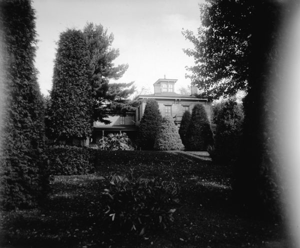View across a well-manicured yard with sculpted shrubs in front of a house. Identified as the yard of the Spaulding residence.