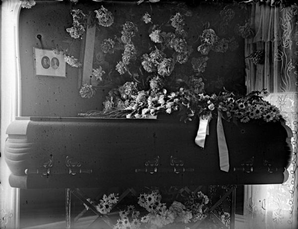 Indoor view of a flower-draped casket in a room.