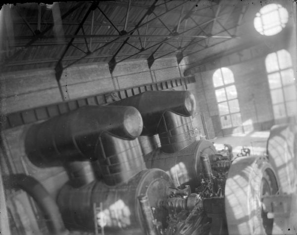 Indoor view of machines in a large brick building with large windows. Identified as the interior of the powerhouse on the Hatfield canal.