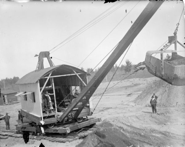 Elevated view of a steam dredge at the construction site of a dam on a river. Identified as the construction of the Hatfield dam in 1907.