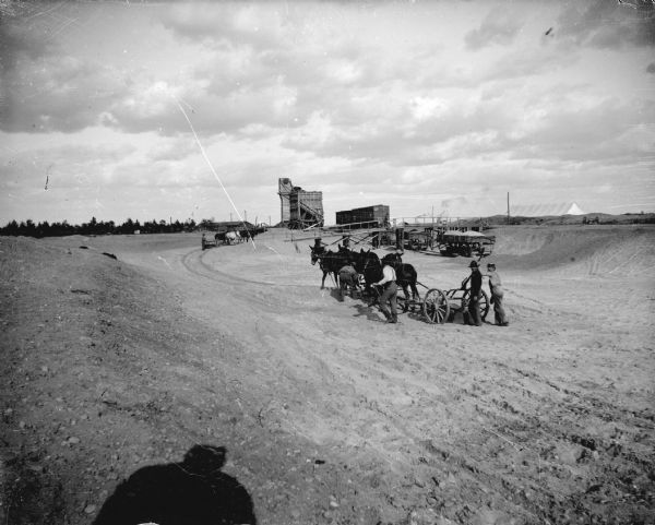 View of men with teams of horses working at a dam construction site. Identified as the construction of the canal at the Hatfield dam.