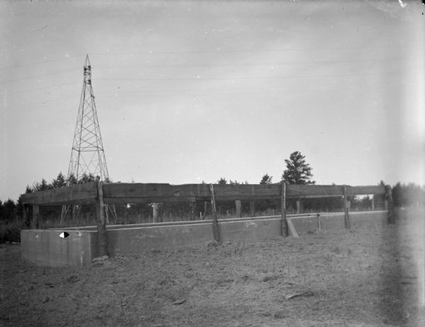 View of a large water tank for cattle. Identified as the water tank owned by C.L. MacDonald.