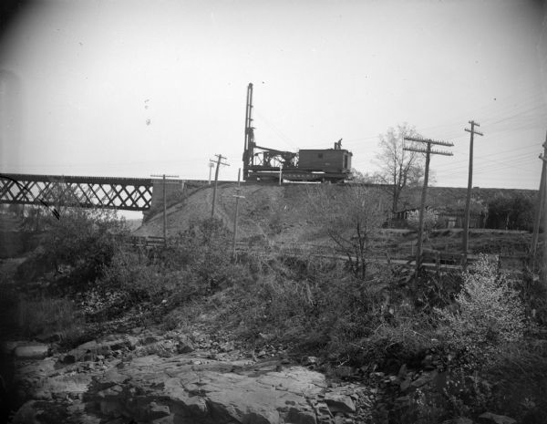 View towards railway machinery on railroad tracks approaching a bridge.