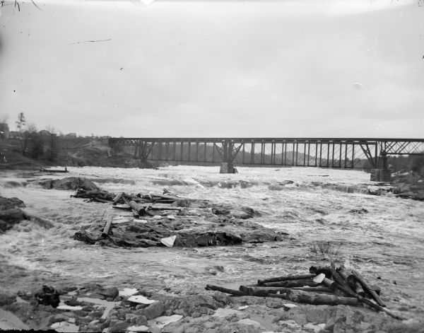 View towards a railroad bridge across a river. Identified as the railroad bridge across the Black River after 1885.