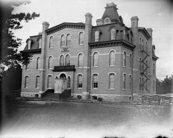 View across lawn towards the front of a large brick school building. Identified as Union High School