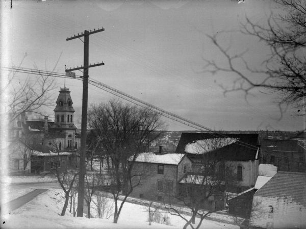 Elevated view of a town covered with snow. Identified as the Jackson County Court House on the left, and the home of Charles J. Van Schaick on the right.