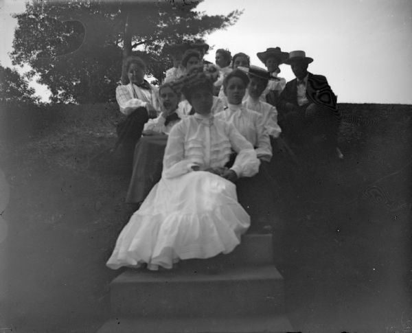 Outdoor portrait of women and men posing sitting on a set of stairs on a hill.