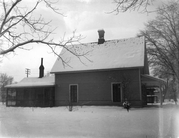 Outdoor portrait of a wooden house surrounded by snow-covered ground.