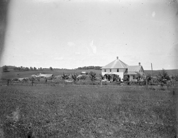Outdoor portrait of a wooden house surrounded by young trees in the distance.