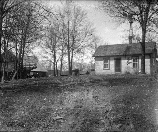 Outdoor portrait of a small wooden house and bare trees in the yard.