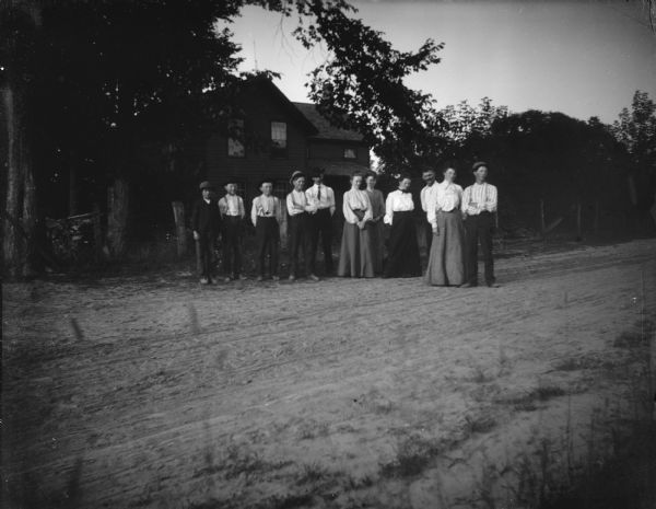 Outdoor view of a group of men and women posing standing on a road in a town.