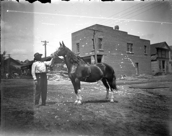 Exterior view of a man posing standing and displaying a horse.