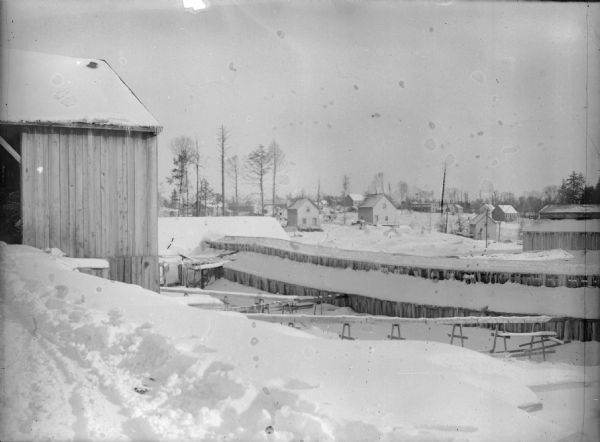A view of wooden buildings and dwellings covered in snow.