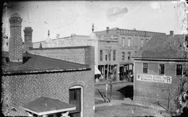 Elevated view of First and Main Streets. A banner promoting the 1891 Wisconsin State Fair is posted on the side of a building.
