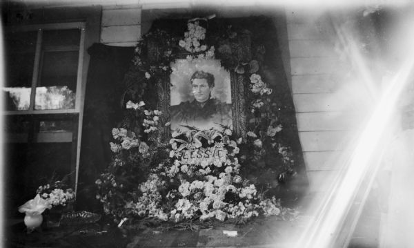 Floral arrangement and photograph of a woman, in memoriam of "Lessic".