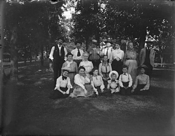 Outdoor view of a large group of men, women, and children posing standing and sitting.