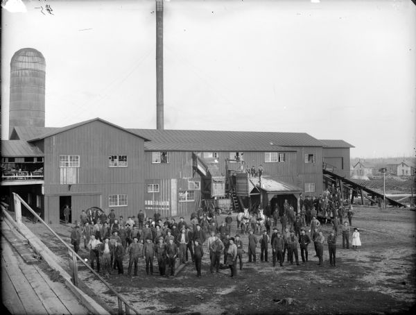 Elevated view of a group of employees assembled in front of a sawmill.