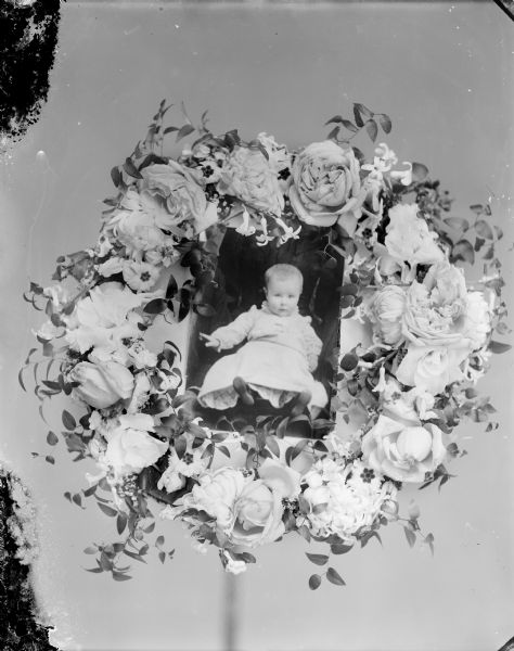 Floral grave memorial with a photograph of a European-American child in the center.