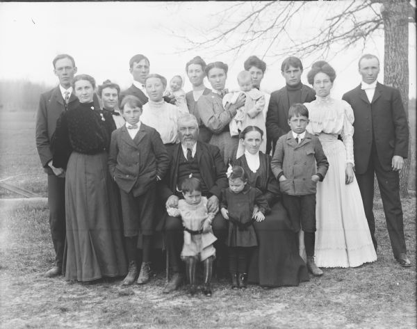 Outdoor group portrait of a large extended family. Identified as probably the family of George Thompson.