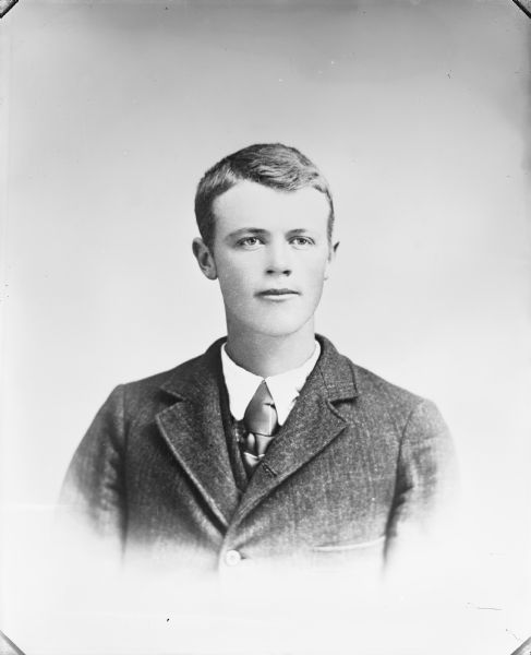 Copy photograph of a quarter-length vignetted studio portrait of a European American man. He is wearing a dark-colored suit coat and neck tie.