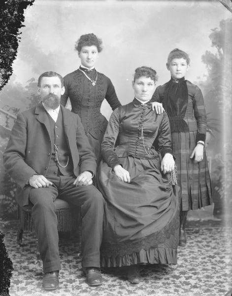Studio group portrait of a family, including a man, two women, and a girl.